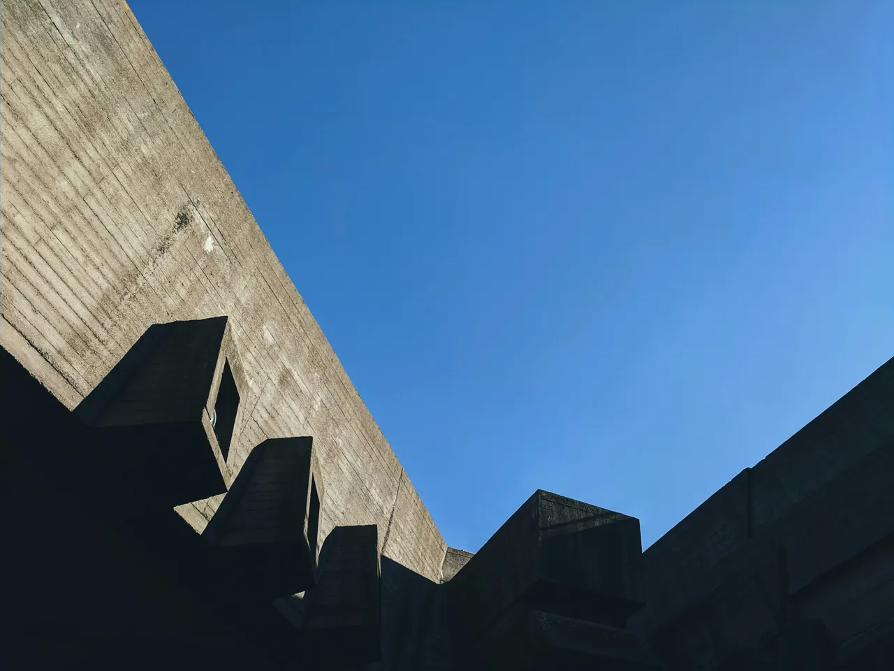 A concrete building seen from below — hard edges, fixed limits
