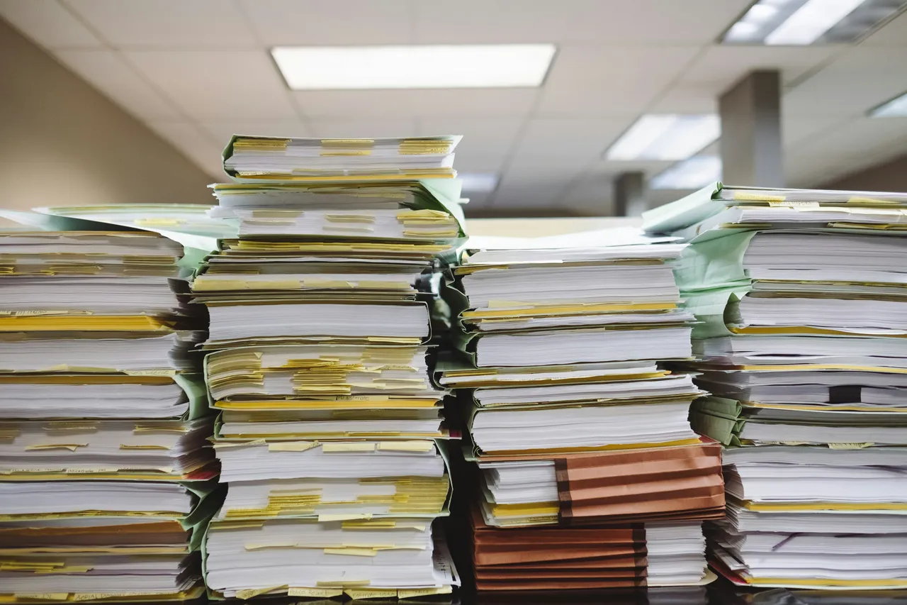 Stacks of document files with index tabs — the manual work in question